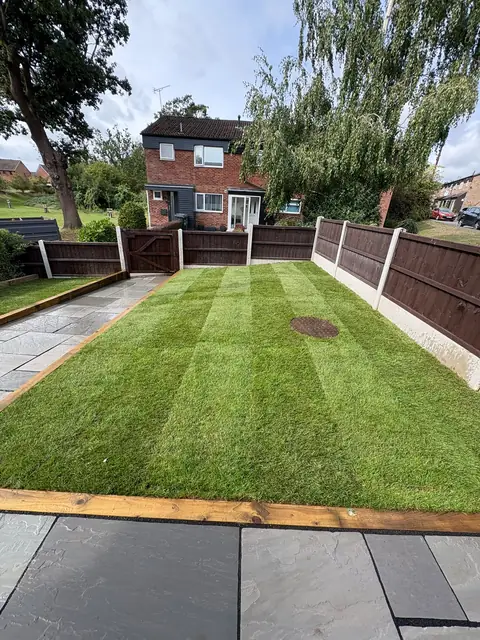 A striped lawn with a grey slab path running down one side